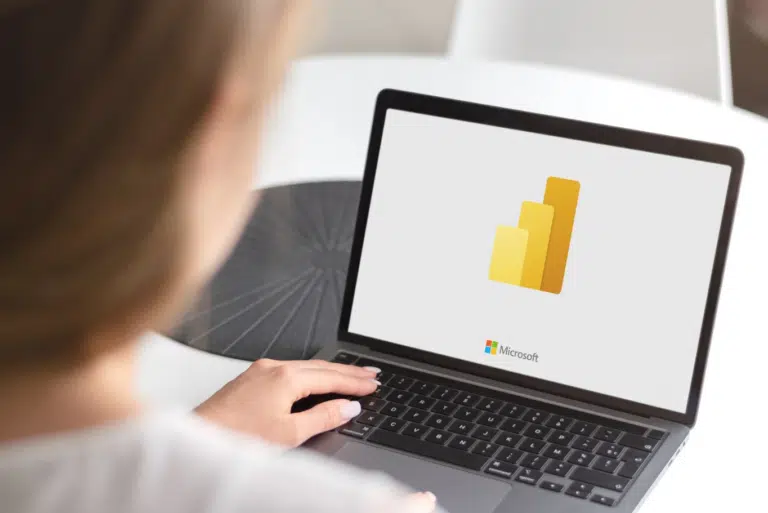 This is an image of the Microsoft Power BI loading screen on a laptop with a person working behind it.